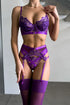Dominique Royal Desire Lingerie Set in vibrant purple with floral embroidered underwire bra, strappy garter design, matching thong and sheer thigh-high stockings.